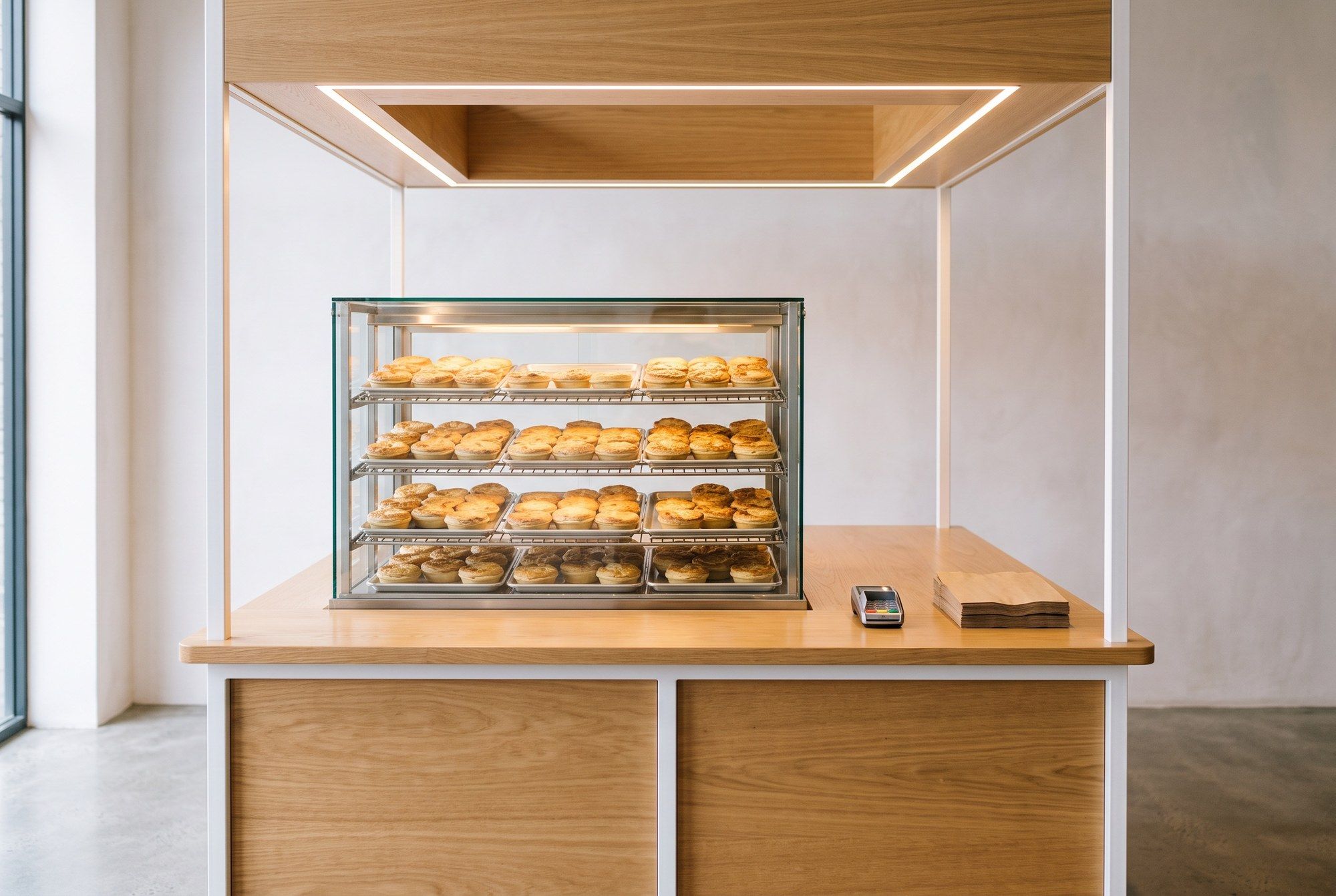 A small mall-basement takeaway counter with a warmer full of round golden pies